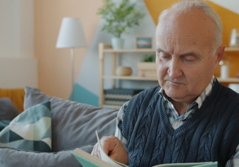 Pessoa idosa lendo em casa, em ambiente confortável e acolhedor